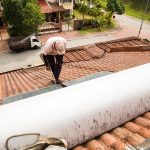 man fixing solar water heater on the roof
