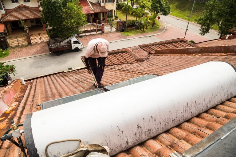 man fixing solar water heater on the roof