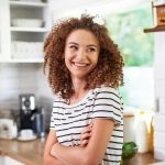 young woman in her small kitchen smiling