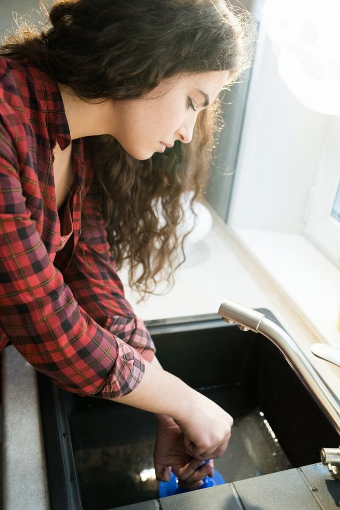 woman clearing clogged drains
