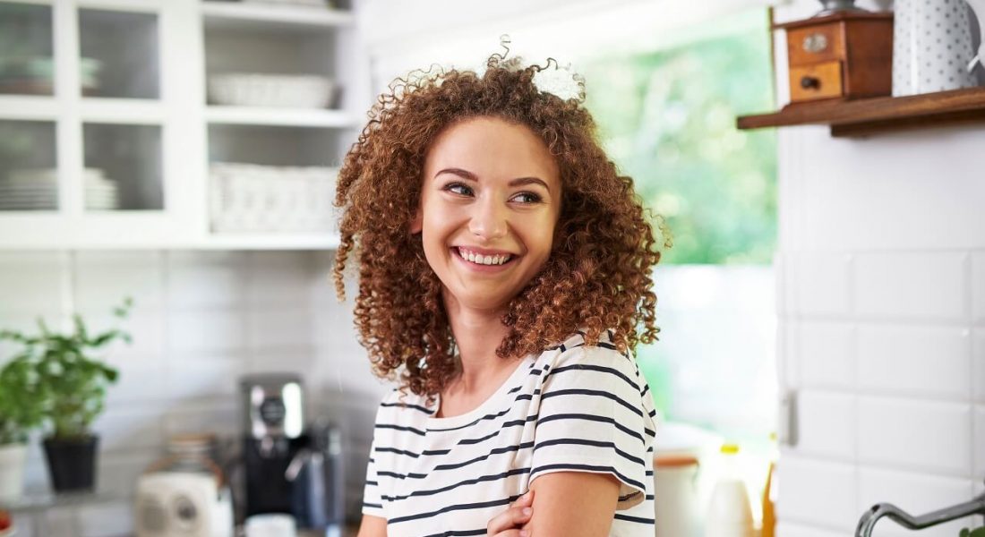 young woman in her small kitchen smiling